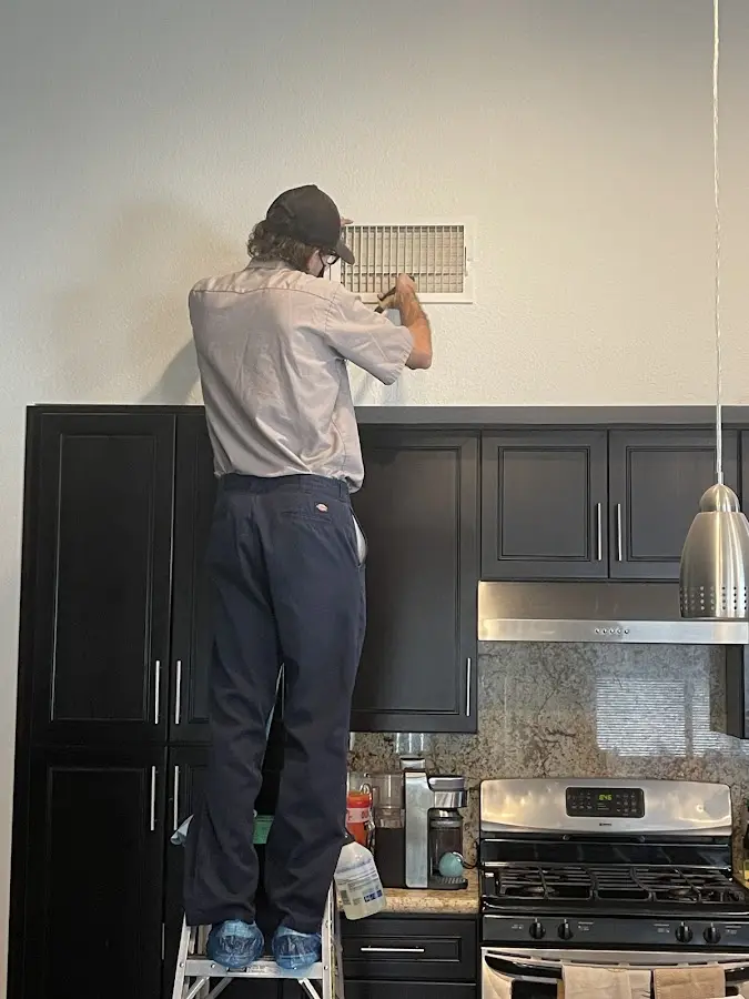 Technician inspecting an air vent during HVAC service in New Castle